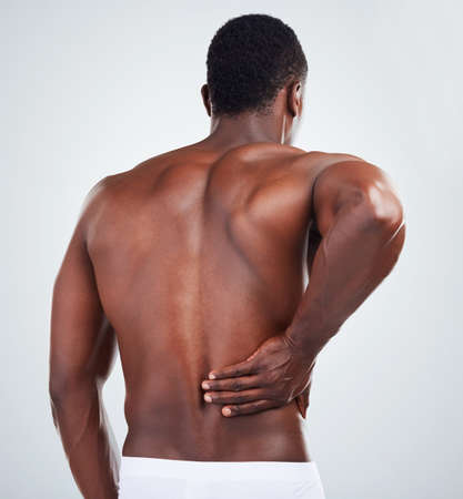 One unknown muscular fitness model experiencing back pain from poor posture while exercising. Black...