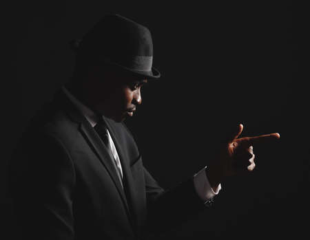 Dapper and confident young man dressed in formal attire against a dark background. Handsome african american male looking stylish and sophisticated isolated on black. Looking very classy and debonairの写真素材