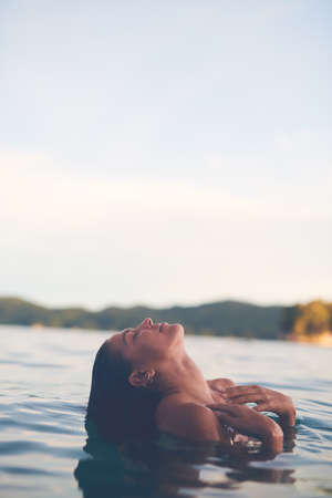 Sexy young woman swimming in the sea. Enjoying a summer vacation and relaxing weekend.の写真素材