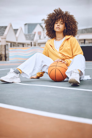 Mixed race woman posing on a basketball court. Beautiful basketball player posing confidently outsideの写真素材
