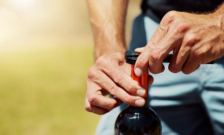Closeup of one unknown farmer opening a bottle of red wine on a farm. Caucasian man standing alone and getting ready for a wine tasting during summer on his vineyard. Weekend wine and alcohol tastingの写真素材