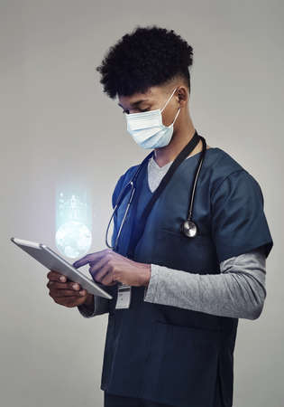 Wear your mask, its good for the numbers. Shot of a male nurse holding a digital tablet while...