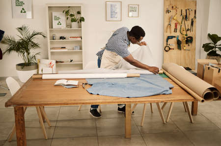 African american designer looking at fabric. Young fashion designer checking roll of material....