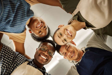 Portrait of group of fashion designers huddles together. Happy tailors united in a circle from below. Diverse businesspeople collaborating together.Professional entrepreneurs together in a circleの写真素材