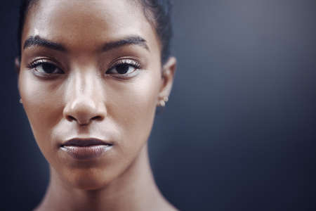 Closeup portrait of one focused mixed race woman with copyspace against a grey background. Face of...