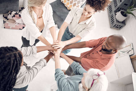 Group of five diverse businesspeople piling their hands together in an office at work. Business...