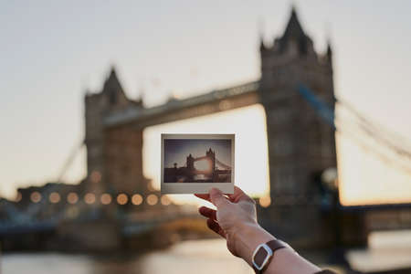Thanks for the memories. Shot of an unrecognisable woman holding a photograph while standing next to the Tower Bridge in London.の写真素材