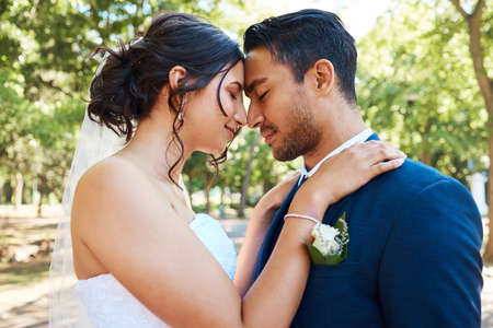 Bride and groom standing together and touching foreheads while standing together on their wedding...