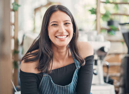 Portrait of one happy young hispanic waitress working in a store or cafe. Friendly woman and coffeeshop owner managing a successful restaurant startupの写真素材