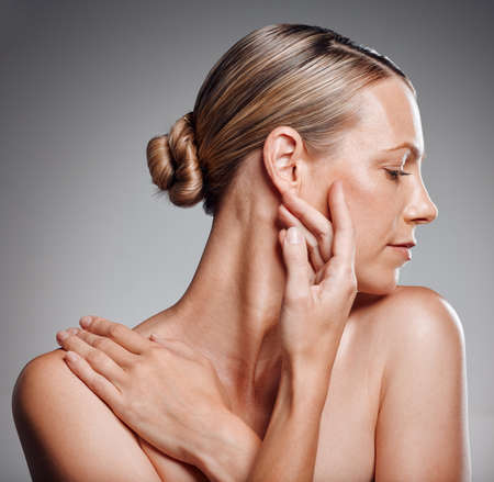 Beautiful mature woman posing in studio against a grey background. Beautiful mature woman posing in studio against a grey background.の写真素材