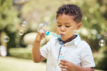shot of a little boy blowing bubbles in a garden at home.
