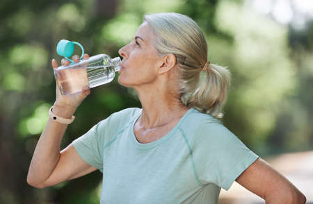 Cooling down after her morning run. Shot of a mature woman drinking water while exercising outdoors.