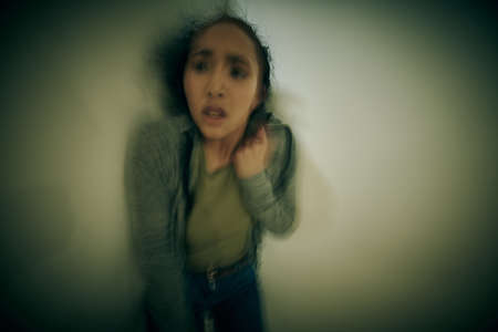 One mixed race female suffering mental illness in asylum. Hispanic woman having panic attack after...