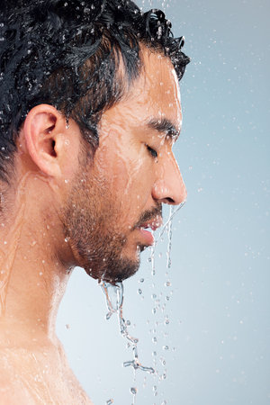 Man water running down his face in the shower. Young man washing his face. Man standing under the water in the shower. Young mans hygiene routine in the shower. Closeup of face of young man showeringの写真素材