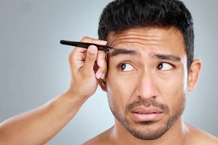 They just need a little shaping. Shot of a handsome man getting his eyebrows tweezed.
