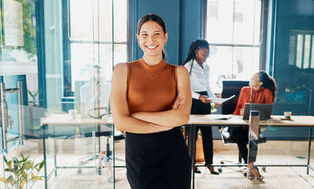 Doing business with confidence. Cropped portrait of an attractive young businesswoman standing with her arms folded in an office doorway.の写真素材