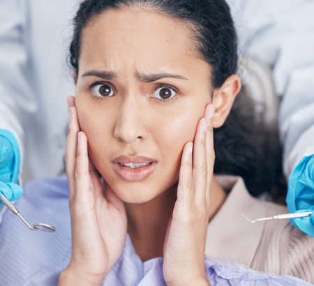 Shot of a young woman looking afraid at her dentists office.