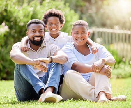 We love bringing him to the park for some fun. Portrait of a happy family relaxing together on the lawn outdoors.の写真素材