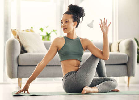 Yoga a day keeps the doctor away. Shot of a young woman practising yoga in her living room.
