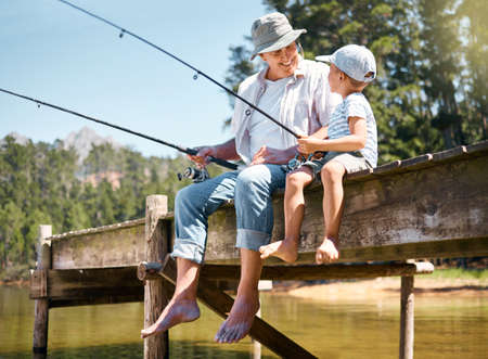 Grandpa will teach him all he needs to know. Shot of a little boy fishing with his grandfather at a...