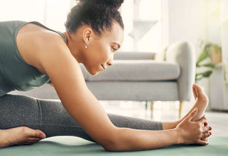 Shot of a woman stretching on her exercise mat at home.