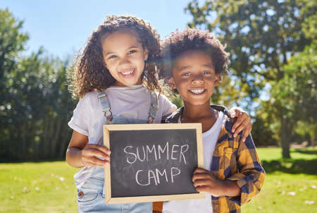 Two besties in a summer camp pod. Shot of a two friends holding a sign in a outside in a park.の写真素材