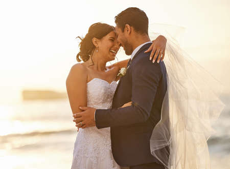 Ill stand by your side in the good and the bad. Shot of a young couple on the beach on their wedding day.の写真素材