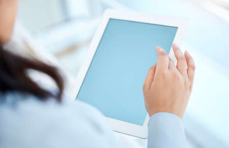 Closeup shot of an unrecognisable businesswoman using a digital tablet with a blank screen in an...