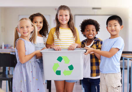 Young children are naturally curious and observant. Shot of a group of preschoolers holding a recycling bin in class.の写真素材