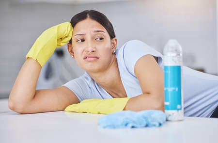 Shot of a young woman looking unhappy while doing chores at home.の写真素材
