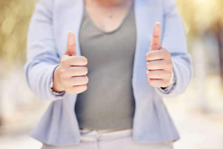Closeup shot of an unrecognisable businesswoman showing thumbs up outdoors.の写真素材