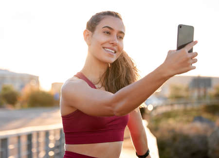 Mandatory workout selfie. Shot of a young woman taking a selfie while on a run outside.の写真素材