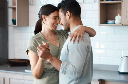 Shot of a young couple dancing in the kitchen at home.の写真素材