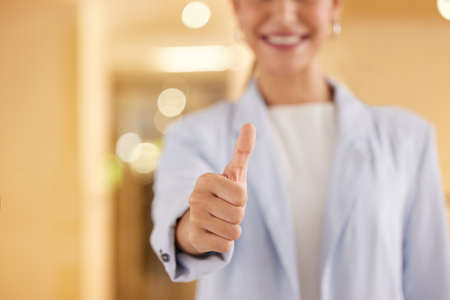 Keep at it with all your efforts. Closeup shot of an unrecognisable businesswoman showing thumbs up in an offce.の写真素材