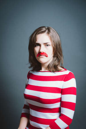 Young woman wearing mask against a grey background in studio. Young woman wearing mask against a grey background in studio.の写真素材