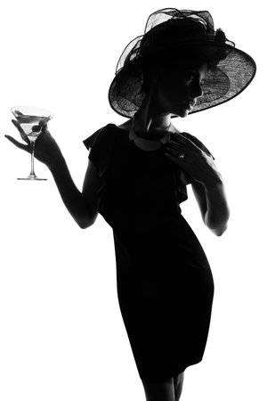 Nothing says class like a martini glass. Studio shot of a stylish woman in silhouette drinking a martini against a white background.の写真素材