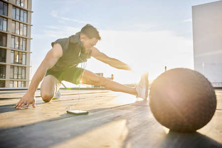 Im only getting warmed up. Shot of a sporty young man stretching while out on a rooftop.