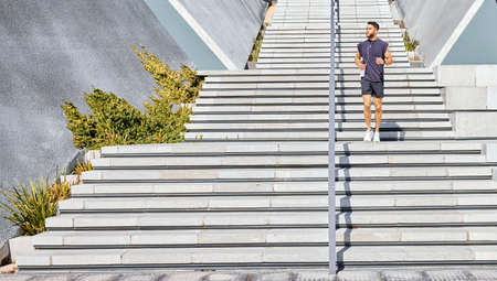 All I need is me and some motivation. Shot of a sporty young man listening to music and carrying a...