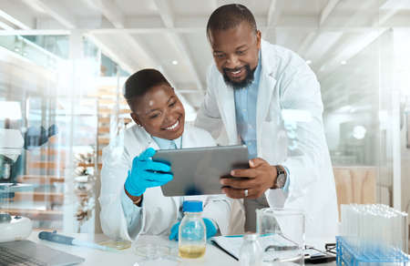 Dive into our world of science. Shot of two scientists using a digital tablet in a laboratory.の写真素材
