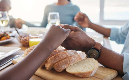 Bless this meal to our bodies oh God. Shot of two unrecognizable people holding hands at the dinner table at home.の写真素材