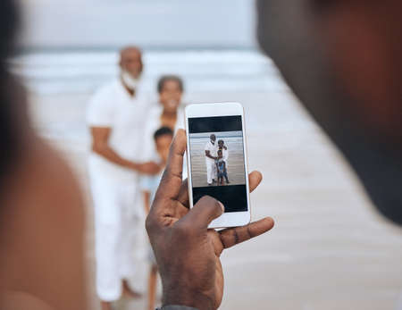 Great quality pictures. Cropped shot of an unrecognizable man taking a picture of a mature couple and their grandson at the beach.の写真素材