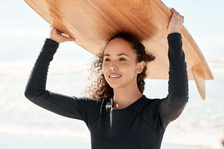 Shot of an attractive young woman carrying a surfboard at the beach.の写真素材