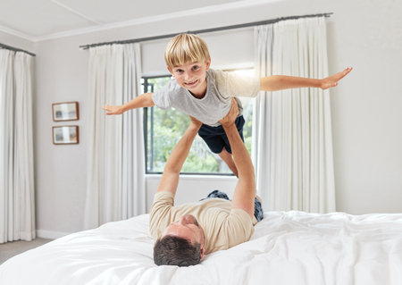 Hes idea of an extreme sport. Shot of a father and son playing in a bedroom at home.の写真素材