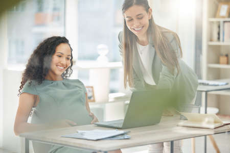 Shot of two young businesswomen working together on a laptop in an office.の写真素材