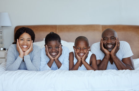 Family means putting your arms around each other. Shot of a beautiful young family bonding in bed together.の写真素材