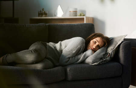 Im not moving today. Shot of a young woman lying on her couch feeling depressed.
