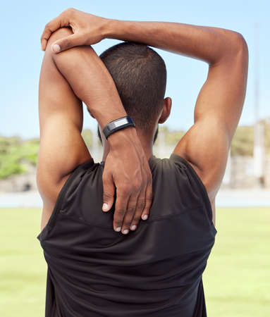 Athletic man preparing for fitness and exercise by stretching and warming up outside on a sports...