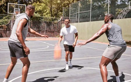 Three african american men playing basketball on a court outdoors. Black man and his sporty friends...