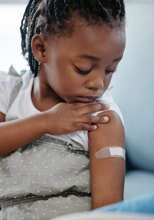Vaccinate to protect your child against many dangerous diseases. Shot of an adorable little girl with a plaster on her arm after an injection.の写真素材
