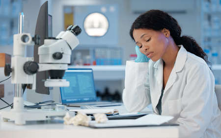 Counting down the hours. Shot of a young woman looking bored while at work in her lab.の写真素材